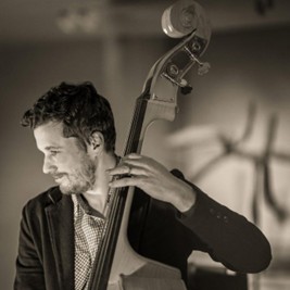 Tom Liddle in greyscale holding a cello